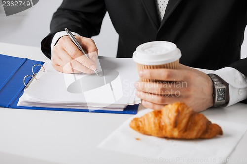 Image of businessman with coffee writing something