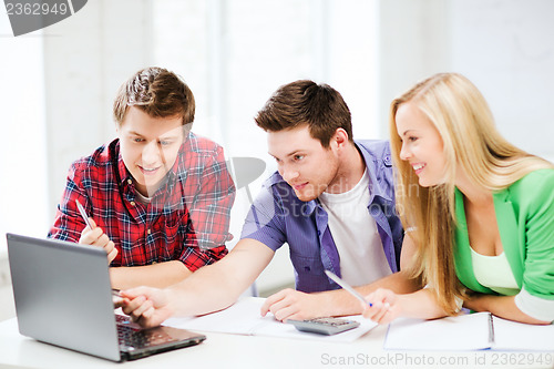 Image of smiling students looking at laptop at school