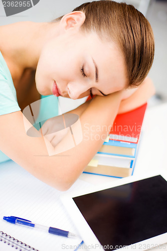 Image of tired student sleeping on stock of books