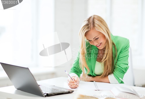 Image of smiling student girl writing in notebook
