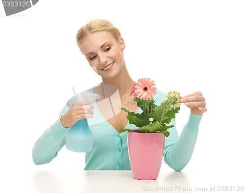 Image of woman holding pot with flower and spray bottle