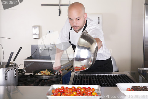 Image of Chef in kitchen cooking, he is working on the sauce for the food