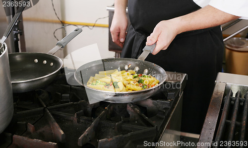 Image of Chef cooking rigatoni with vegetables in a pan