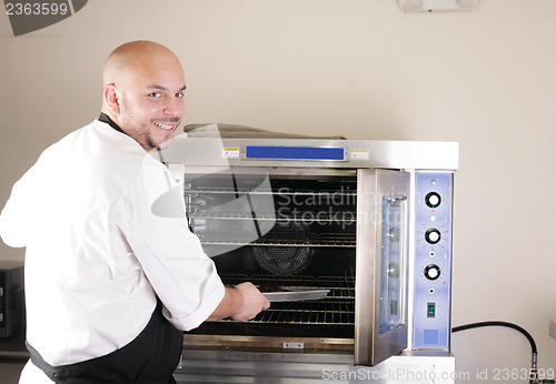 Image of Happy young chef cooking steak in the oven 