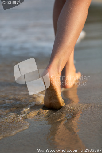 Image of Beautiful woman legs on the beach at sunset