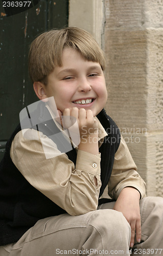 Image of Smiling boy sitting on doorstep