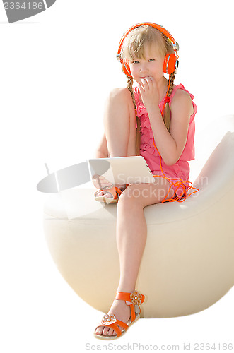 Image of Thoughtful girl doing homework with tablet computer and listenin