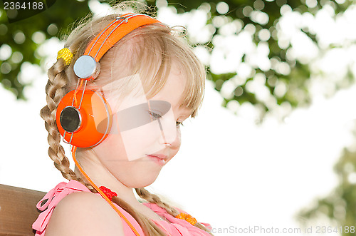 Image of Girl sitting on bench in park and listening language audio cours