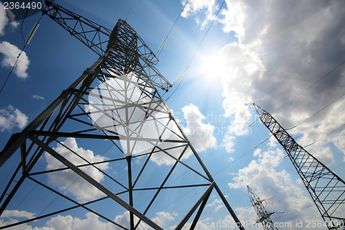 Image of tall electric masts against sun and sky