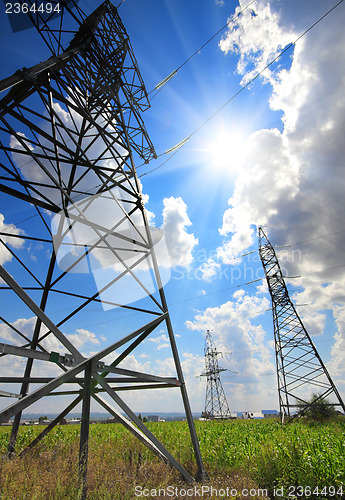 Image of tall electric masts against sun and sky