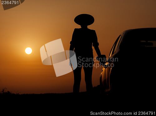 Image of Silhouette woman with hat standing near car