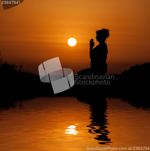 Image of Silhouette woman sitting and relaxing against orange sunset