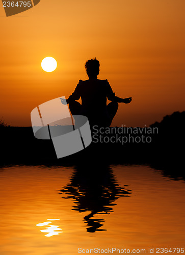 Image of Silhouette woman sitting and relaxing against orange sunset