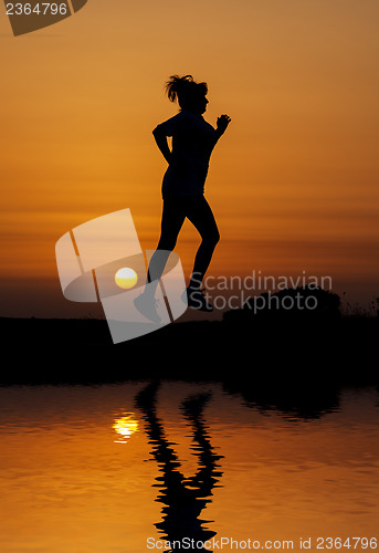 Image of Silhouette woman running against orange sunset