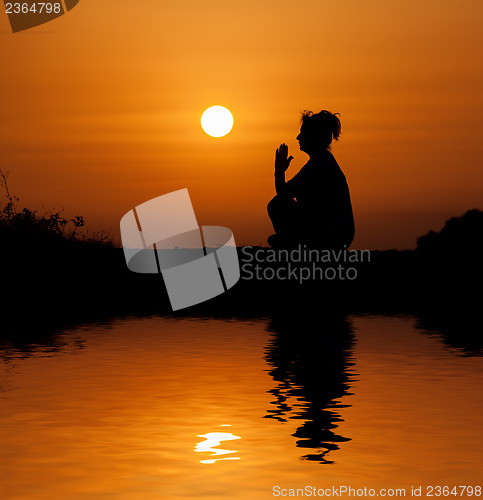 Image of Silhouette woman sitting and relaxing against orange sunset