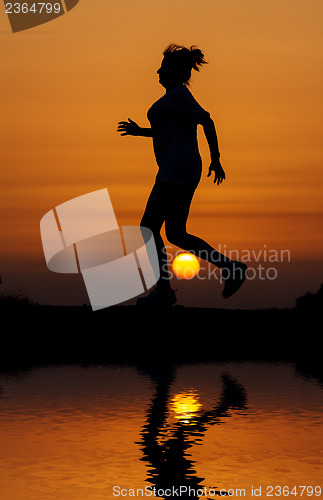 Image of Silhouette woman running against orange sunset