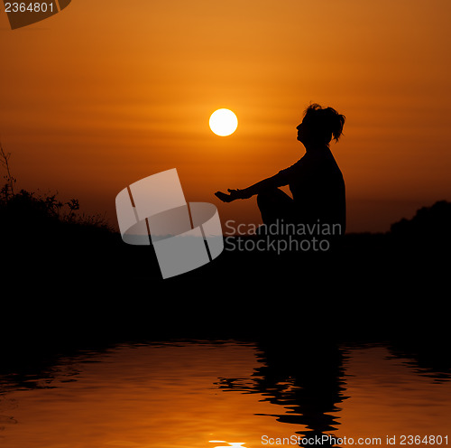 Image of Silhouette woman sitting and relaxing against orange sunset