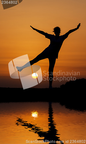 Image of Silhouette woman jumping against orange sunset