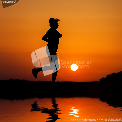 Image of Silhouette woman running against orange sunset