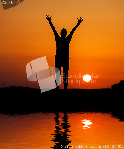 Image of Silhouette woman jumping against orange sunset