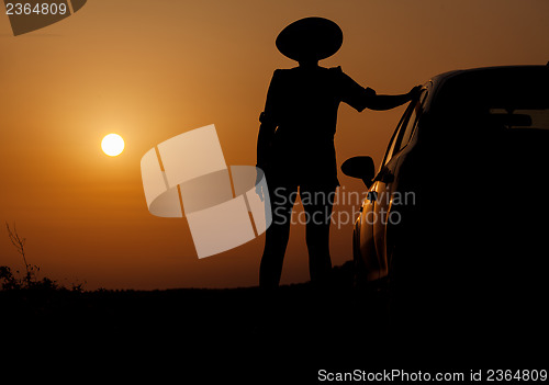 Image of Silhouette woman with hat standing near car