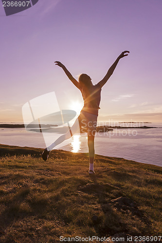 Image of Teenage girl dancing in the sunset