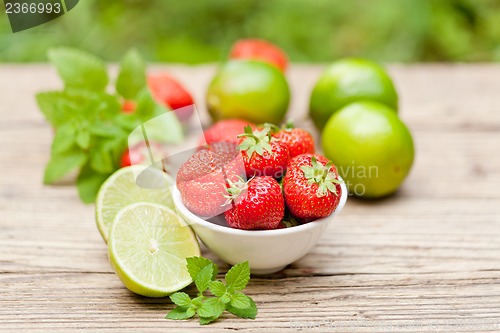 Image of fresh tasty sweet strawberries and green lime outdoor in summer