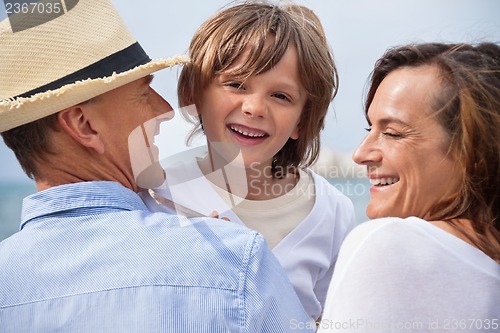 Image of happy family sitting on rock and watching the ocean waves