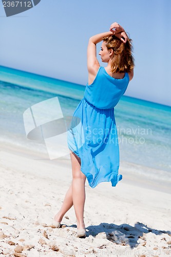 Image of beautiful woman in blue dress on beach in summer