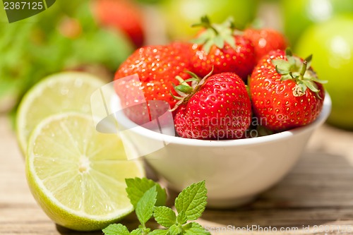 Image of fresh tasty sweet strawberries and green lime outdoor in summer