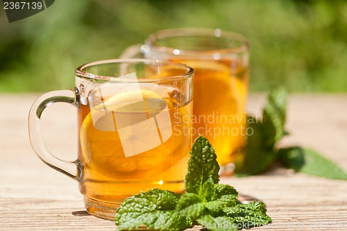 Image of fresh tasty hot tea lemon and mint outdoor in summer 