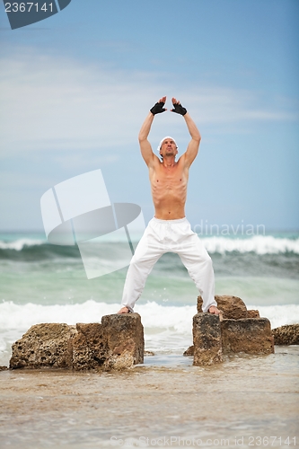 Image of healthy man doing pilates yoga meditation on beach summer