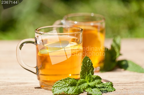 Image of fresh tasty hot tea lemon and mint outdoor in summer 