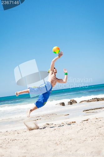 Image of attractive young man playing volleyball on the beach