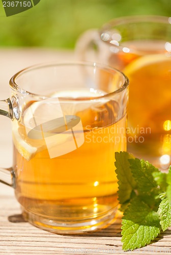 Image of fresh tasty hot tea lemon and mint outdoor in summer 