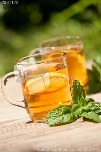 Image of fresh tasty hot tea lemon and mint outdoor in summer 