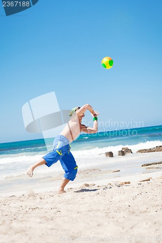 Image of attractive young man playing volleyball on the beach