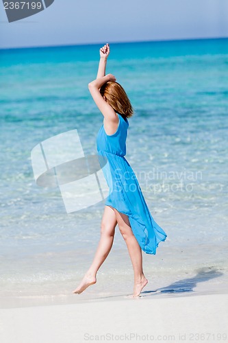 Image of beautiful woman in blue dress on beach in summer