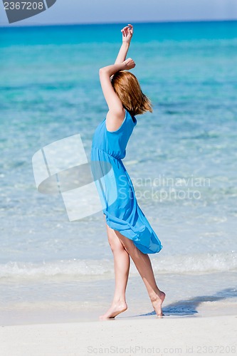 Image of beautiful woman in blue dress on beach in summer