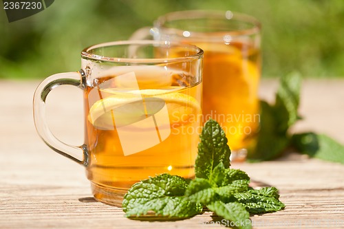 Image of fresh tasty hot tea lemon and mint outdoor in summer 