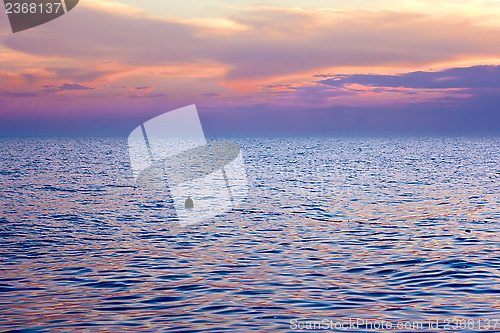 Image of Violet tint clouds over sea after sunset