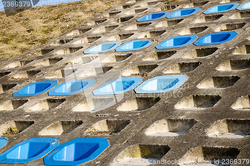 Image of cement slope surface mounted four row blue chairs 