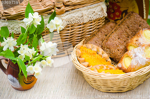 Image of Buns in a wicker basket and a bouquet of jasmine flowers  