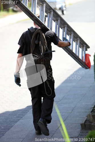 Image of Chimney sweep carrying an extension ladder