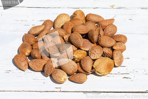 Image of Almonds unpeeled nuts on white wooden background