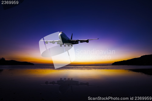 Image of Airplane flying on colorful evening sky over sea at sunset with 