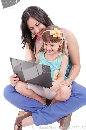 Image of Young mother and daughter looking at laptop.  Focus in the mothe