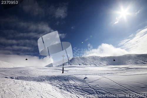 Image of Ski slope, gondola lift and blue sky with sun