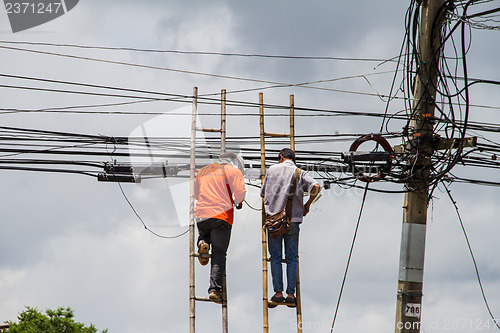 Image of lineman working on cable - telephone pole from ladder