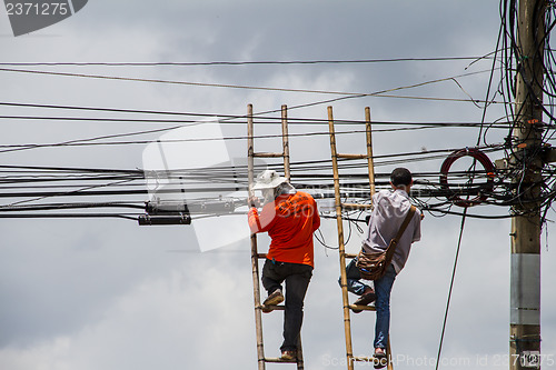 Image of lineman working on cable - telephone pole from ladder